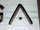Вот фотография, показывающая букву «А», вырезанную с помощью лобзика, и ту же букву после выравнивания краев шлифовальным диском: